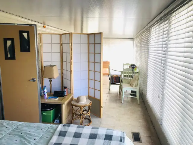 A wide view of a room with a bed, desk, chair, and room divider.