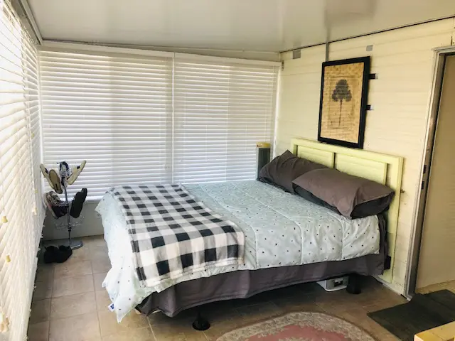 A small bedroom with a bed, window, and door.
