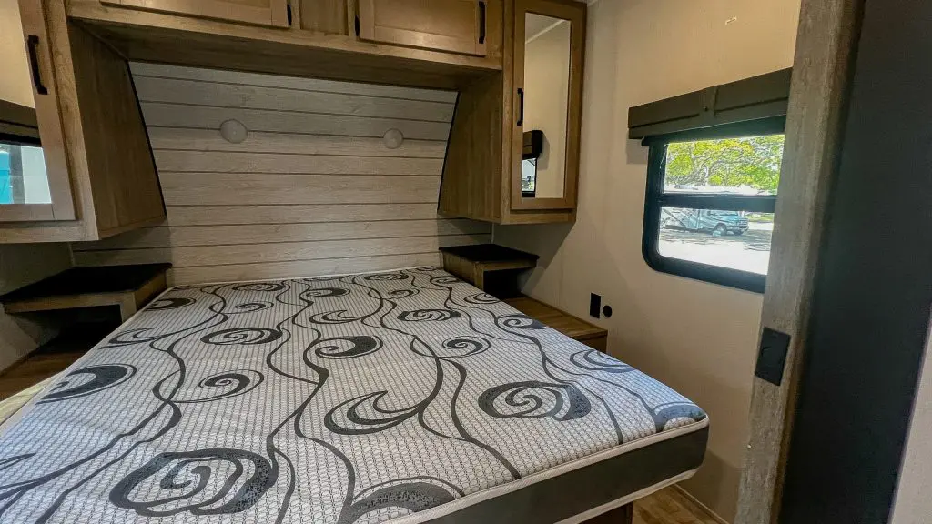 A small room with a bed, cabinets, and a window.