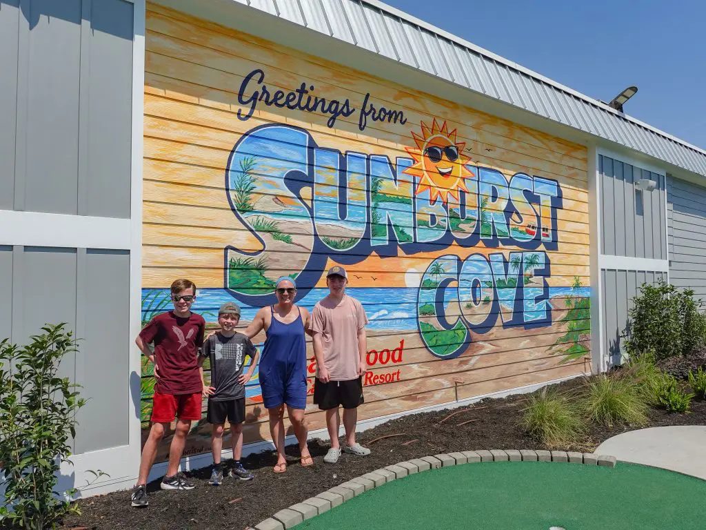 A family stands in front of a colorful mural on the side of a building.