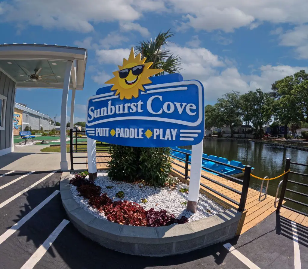 A blue sign with a smiling sun and the words 'Sunburst Cove' in white letters.