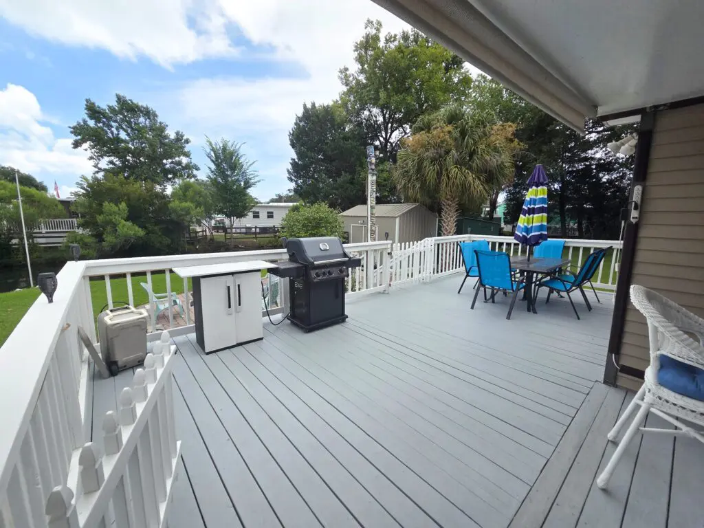 A deck with a grill, patio set, and umbrella.