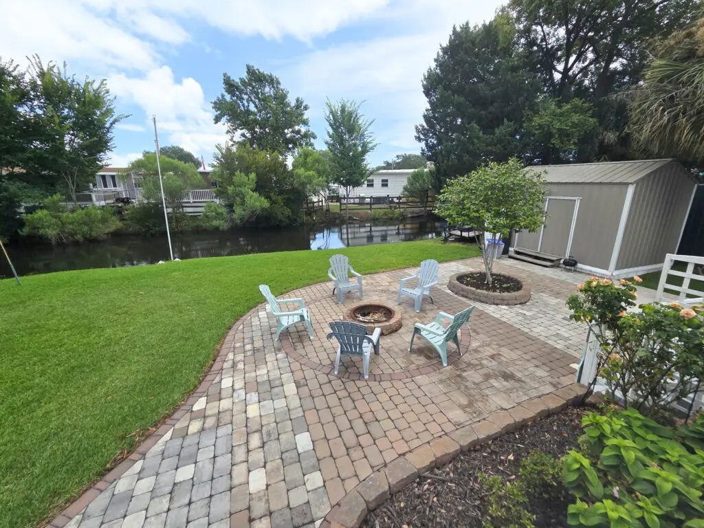 A fire pit with seating area on a brick patio overlooking a canal
