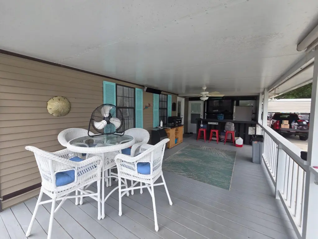 A covered porch with outdoor furniture, a grill, and a bar area.