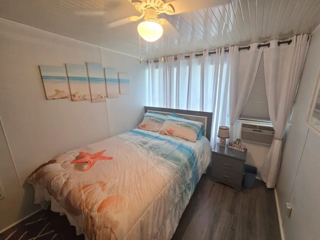 A small guest room with a bed, nightstand, and window.