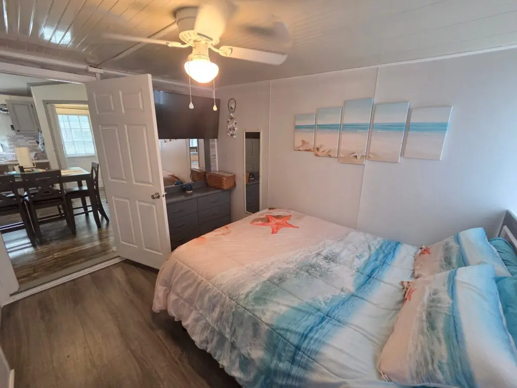 A guest room with a bed, dresser, and ceiling fan