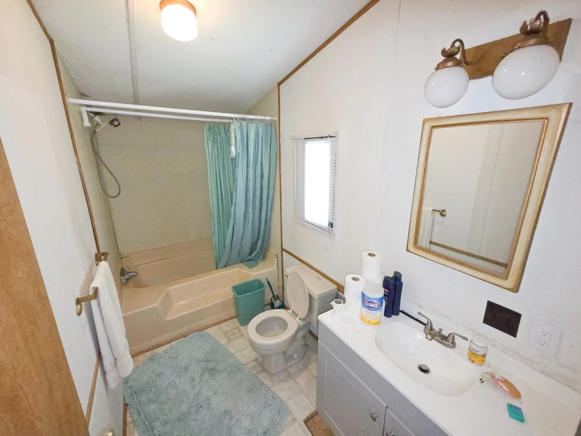 A bathroom with a tub, toilet, sink, and mirror