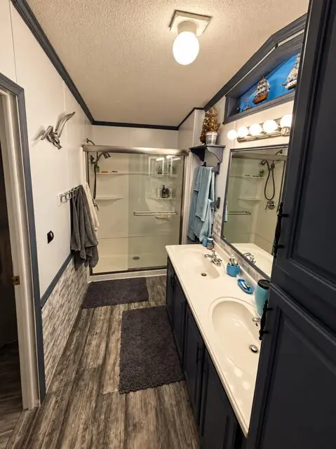 A clean bathroom with a double vanity, glass shower, and mirror.