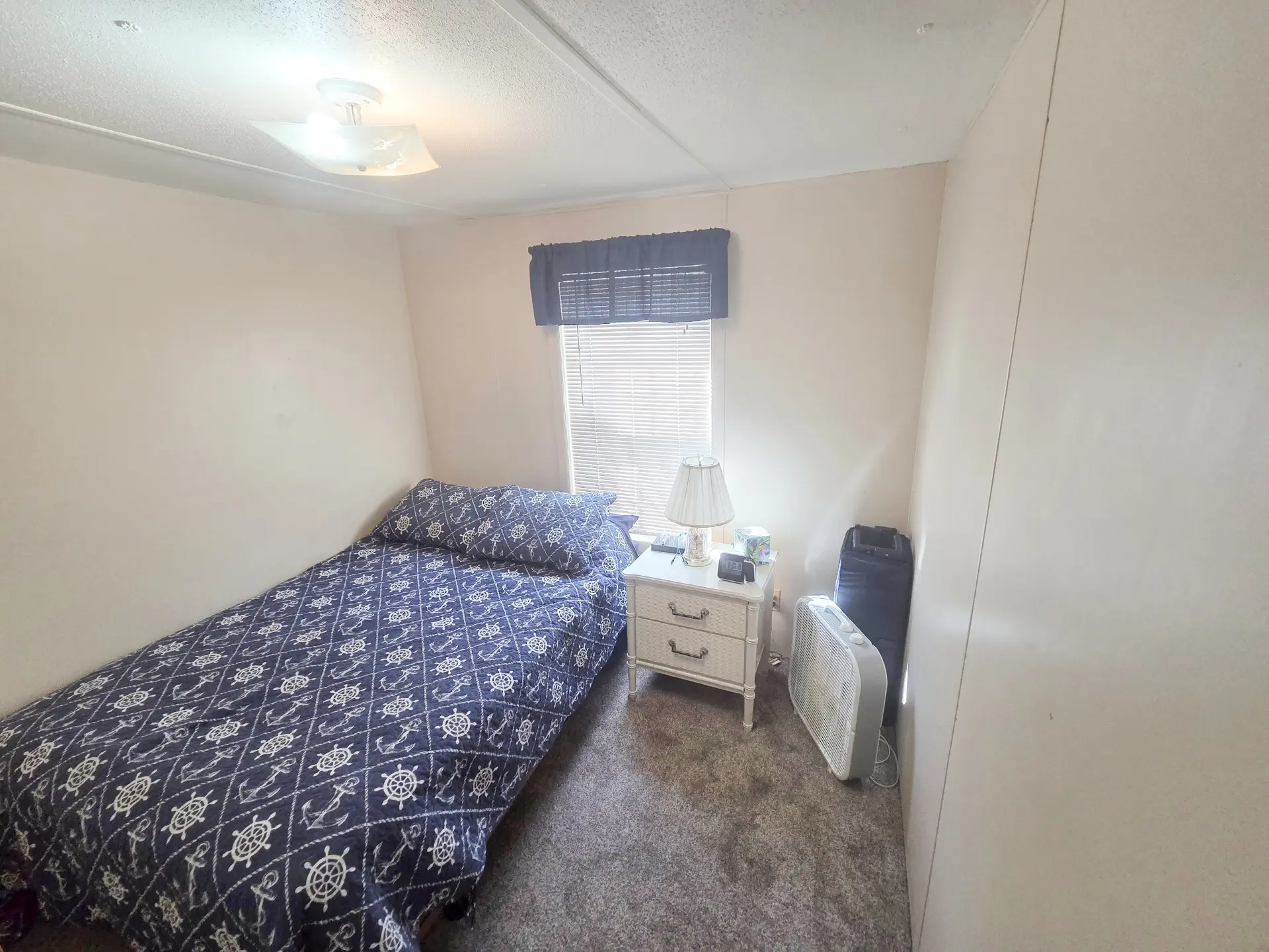 A small bedroom with a single bed, nightstand, and window.