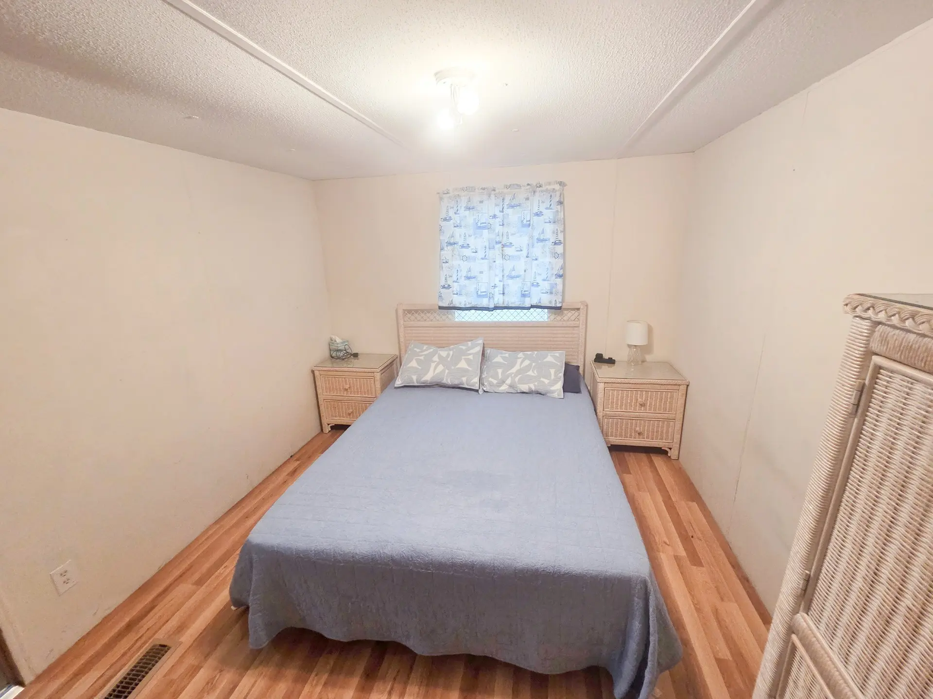 A small, simply furnished bedroom with a bed, two nightstands, and a window.