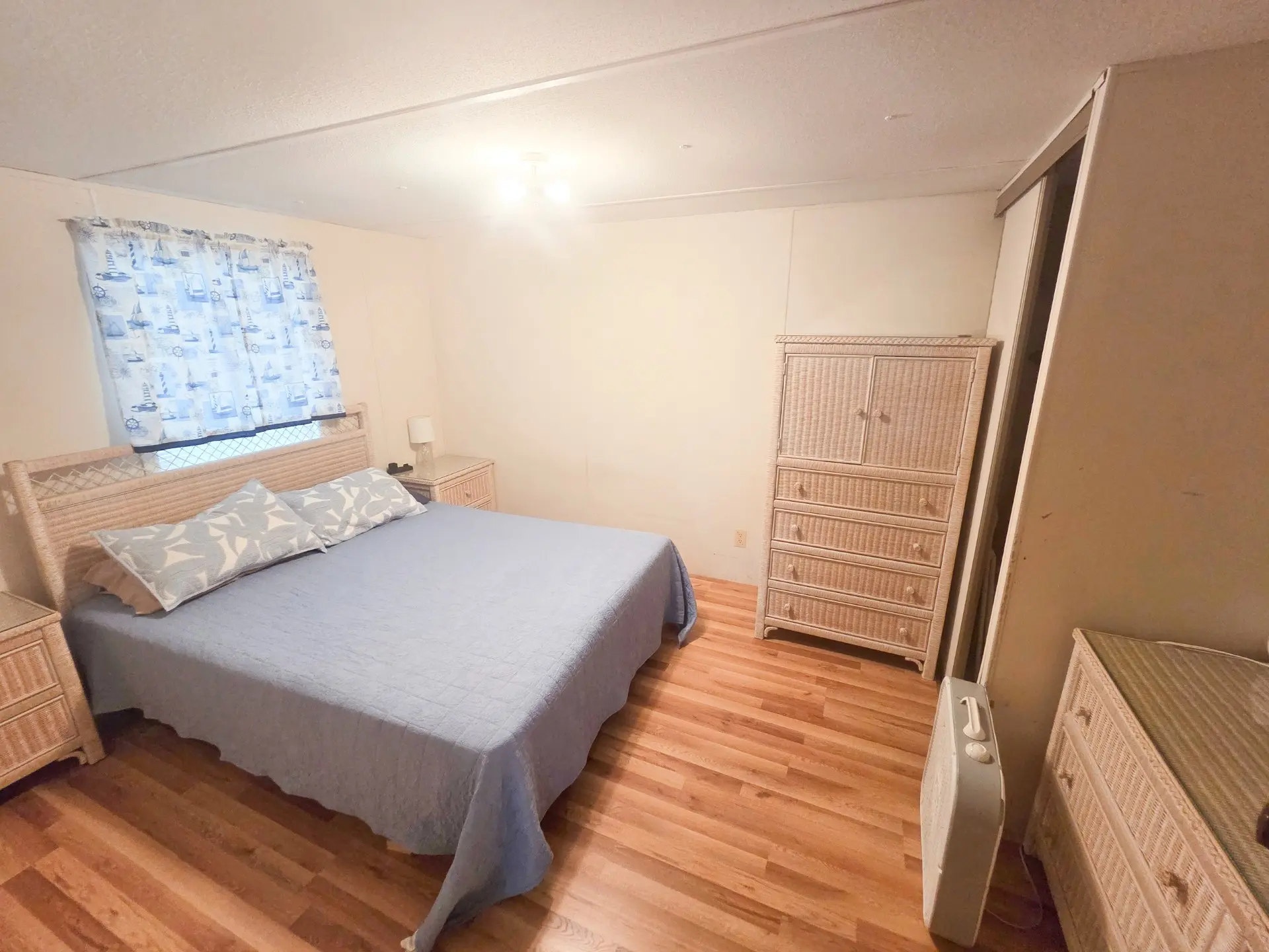 A hotel room with a bed, dresser, and window.