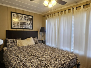 A wide view of a guest room with a bed, nightstand, and window.