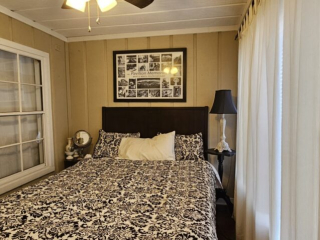 A guest room with a bed, nightstands, a window, and a ceiling fan.