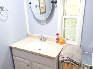 A bathroom sink with a mirror, towel, and window