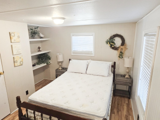 A small bedroom with a bed, two nightstands, and shelves.